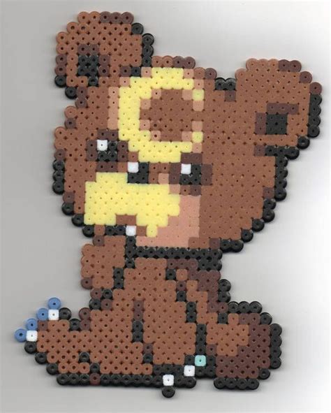 a brown bear made out of legos sitting on top of a white table next to blue buttons