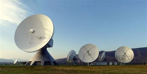 A group of satellite dishes sitting on top of a grass covered field ...