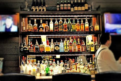 a man sitting in front of a bar filled with liquor bottles