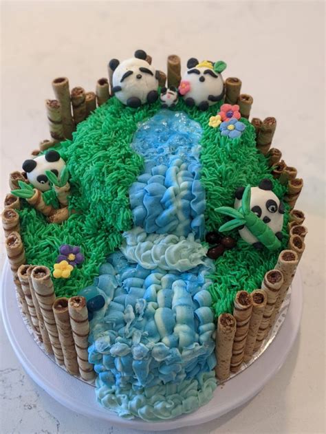 a cake decorated with panda bears and grass