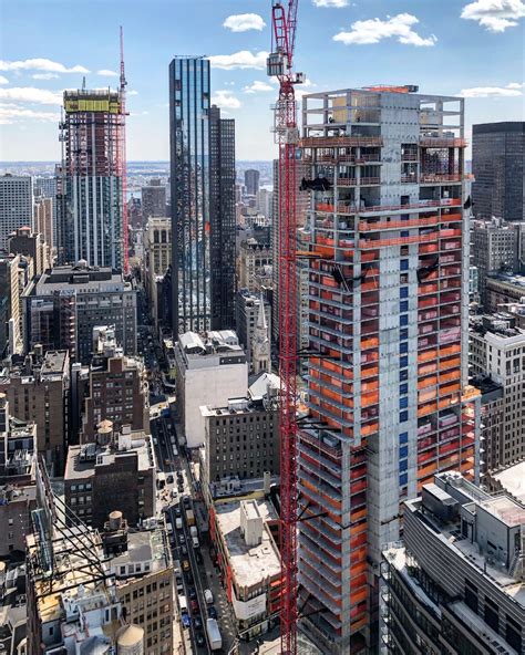 an aerial view of a city with tall buildings and cranes in the foreground, under construction