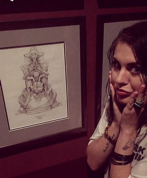 a woman holding her hand to her face in front of a drawing and framed ...