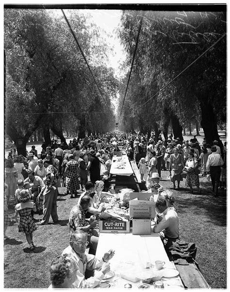 an old black and white photo of people sitting around a picnic table ...