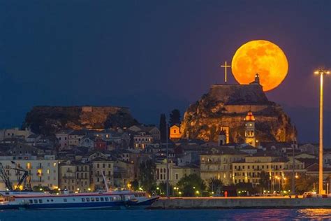 the full moon is setting over an old city