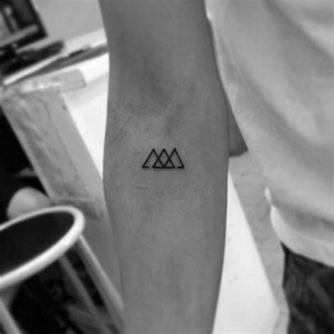 a person with a small tattoo on their arm that has three triangles in ...