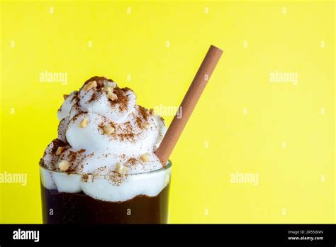 Close-up glass of chocolate milkshake with cream, toasted almonds and cinnamon, brown cardboard ...