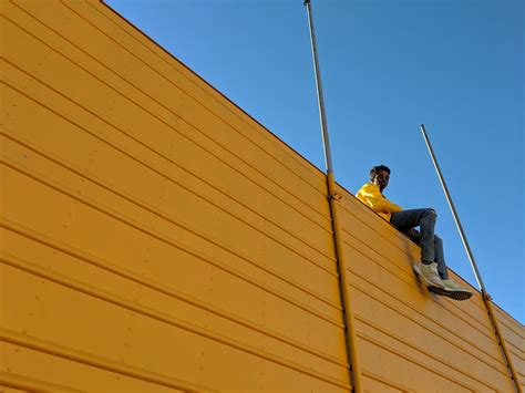 Man Sitting on Top of Yellow Building · Free Stock Photo