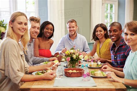 Friends At Home Sitting Around Table For Dinner Party - Stock Photo - Dissolve