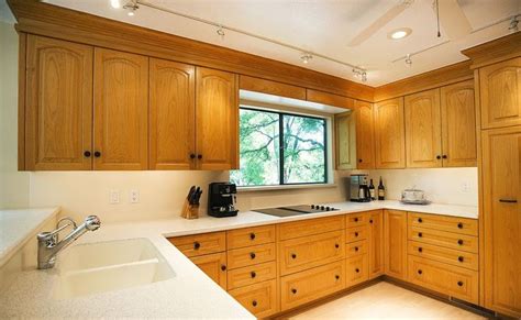 a kitchen with wooden cabinets and white counter tops, along with a window above the sink