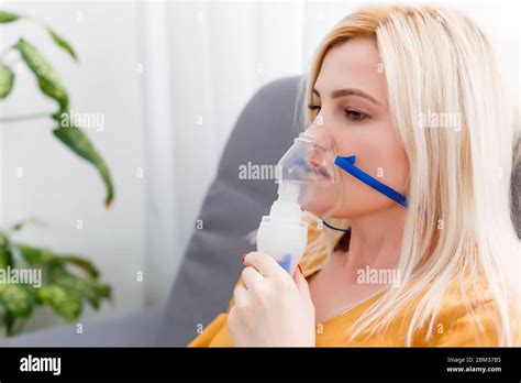 woman makes inhalation nebulizer at home. holding a mask nebulizer ...