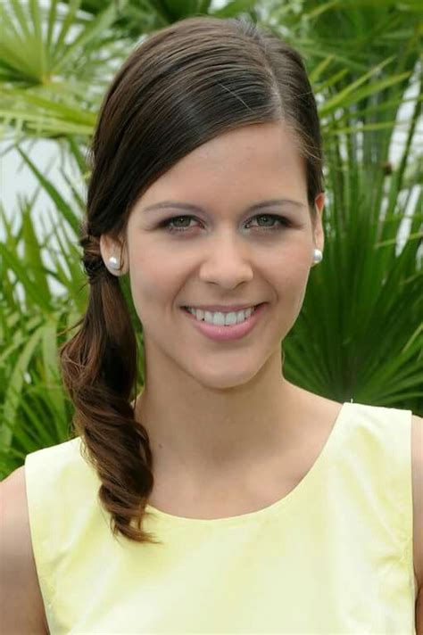 a woman in a yellow dress smiling at the camera with palm trees in the background