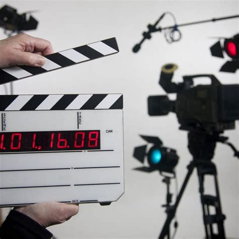 a person holding a clapper in front of a camera set up for a movie