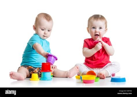 Cute babies playing with color toys. Children girl and boy sitting on floor. Isolated on white ...