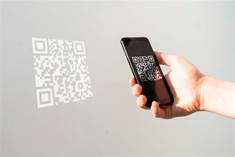 Premium Photo | A hand holding a smartphone and scan the qr code to make a payment