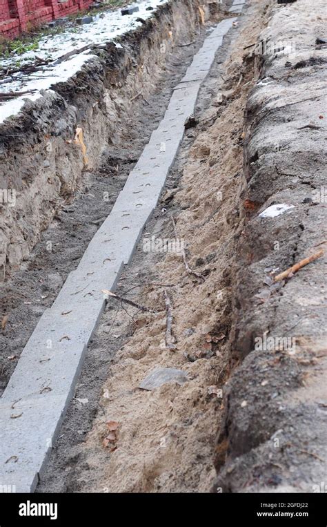 A close-up of a cable trench excavation with underground cables installed and covered with ...