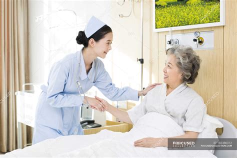 Chinese nurse taking care of senior woman in hospital — Lying Down, smiling - Stock Photo ...