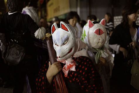 several people wearing cat masks walking down the street at night with ...