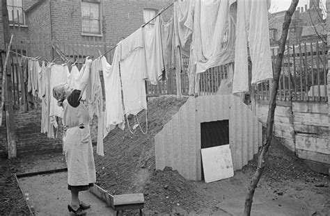 c. 1940 A woman hangs out her laundry next to the new Anderson air raid ...