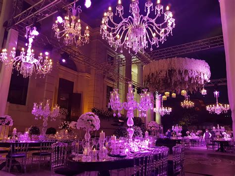 a room filled with lots of tables covered in purple lights and chandelier hanging from the ceiling