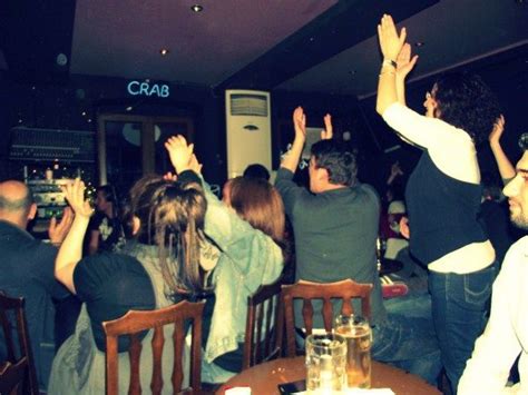 a group of people sitting around a table with their hands in the air at a party