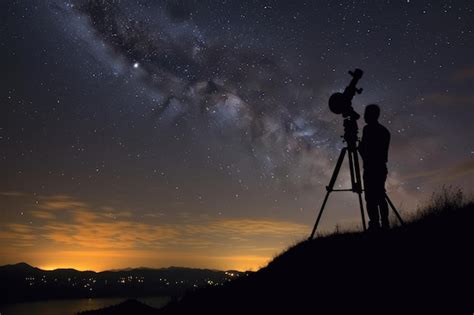 Premium AI Image | A stargazer perches on a hill his telescope pointed towards the night sky's ...