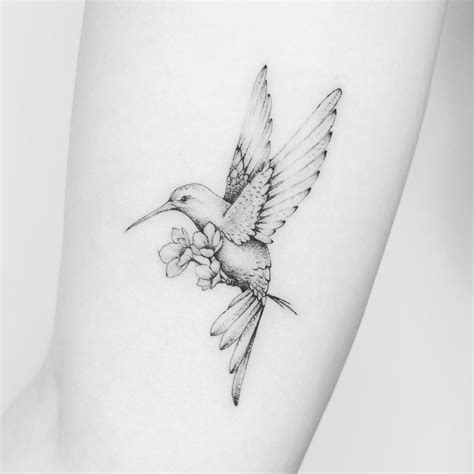 a small tattoo of a hummingbird with flowers