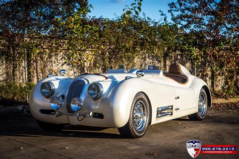 an antique sports car parked in front of a fence