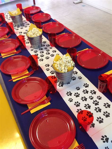 a table set up with red plates and cups filled with popcorn for dogs themed birthday party