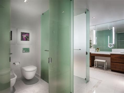 Green glass makes for sophisticated partition walls in the master bathroom, separating the ...