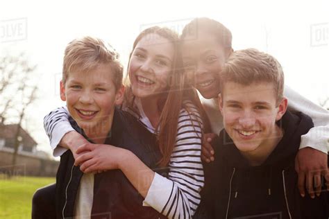 Portrait of teenage friends hanging out in park together - Stock Photo - Dissolve