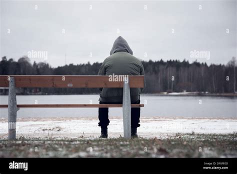 A hooded man sitting alone on park bench Stock Photo - Alamy