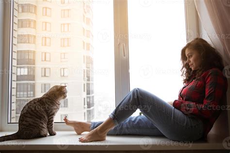 Cat and girl are sitting near the window 3265646 Stock Photo at Vecteezy