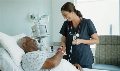 Smiling nurse handshaking with senior patient lying on bed in hospital ...