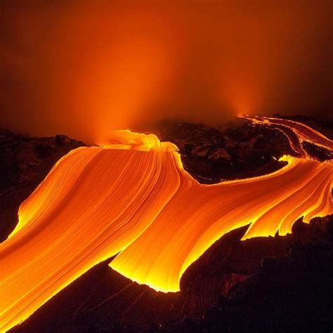 an aerial view of a lava flow in the night sky, with bright orange lights