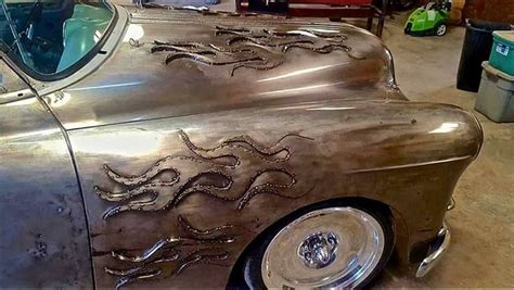 an old silver car with dragon designs on it's hood is parked in a garage