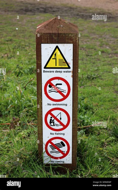 Pond warning signs in a park on a wooden post advising of deep water ...