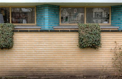 a brick building with three windows and plants growing on the outside ...