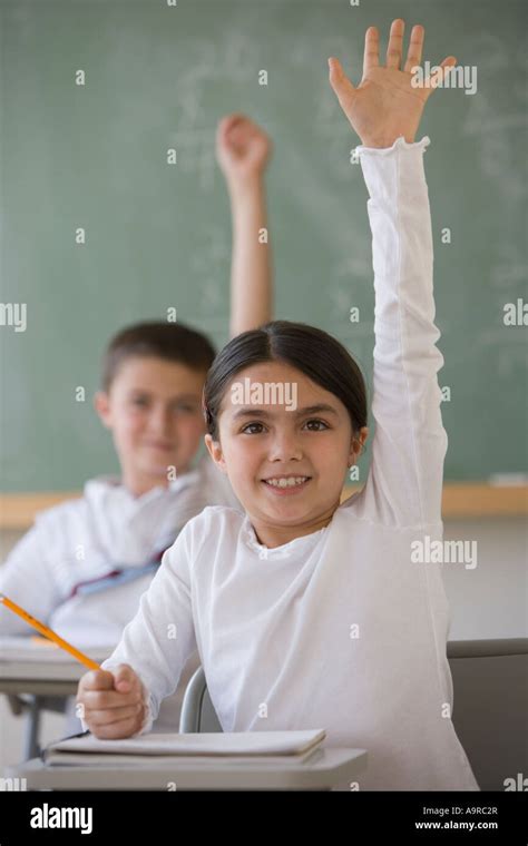 Girl raising hand in classroom Stock Photo - Alamy