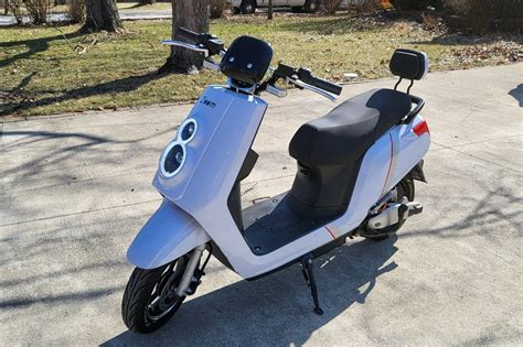 a scooter is parked on the sidewalk in front of some trees and grass