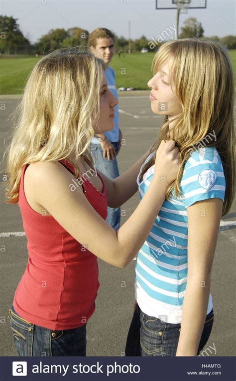 two young women standing in a basketball court talking to each other ...