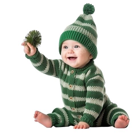 Baby In A Funny Knitted Costume Is Reaching For A Christmas Ornament On A Christmas Tree ...
