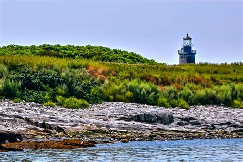 a lighthouse on top of a hill next to the ocean with trees in the background