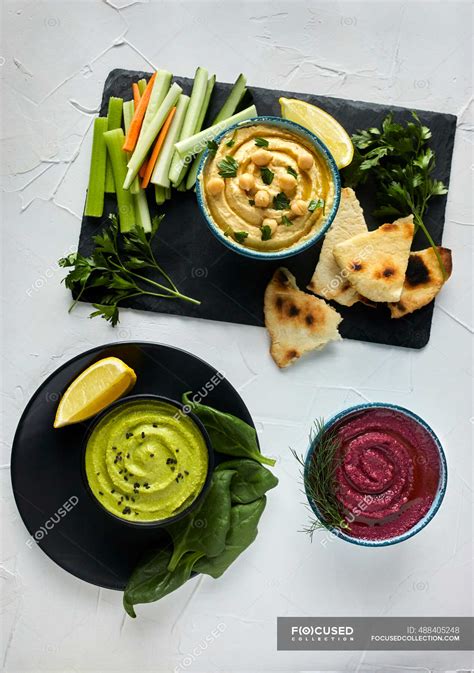 Various types of hummus served with fresh vegetables and pita bread ...