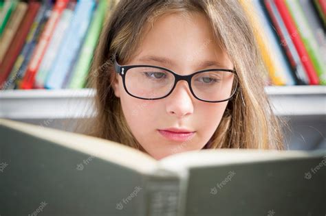 Premium Photo | A girl with glasses is reading a book.