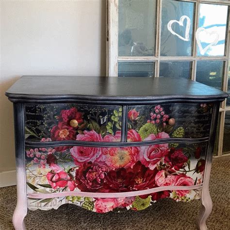 an old dresser with flowers painted on the front and sides, sitting in ...