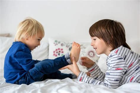 Brothers, playing at home, tickling feet laughing and smiling Stock Photo by ©t.tomsickova 322998400