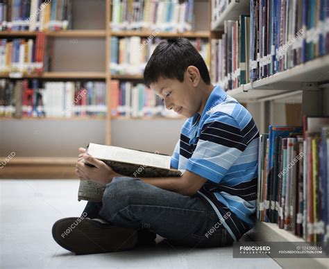 Boy in a library reading a book. — shelf, youth - Stock Photo | #124356516