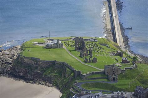 an aerial view of a castle on the coast with green grass and water ...