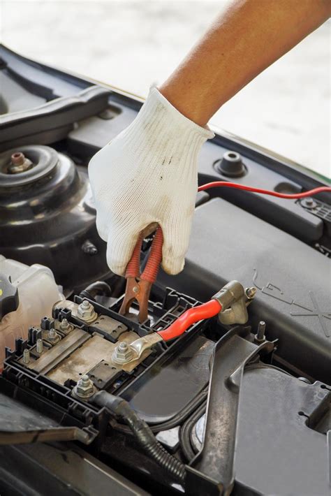 Mechanic is using electric car battery charger through jumper wires ...