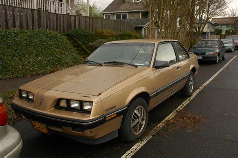 OLD PARKED CARS.: 1985 Pontiac Sunbird SE Turbo.